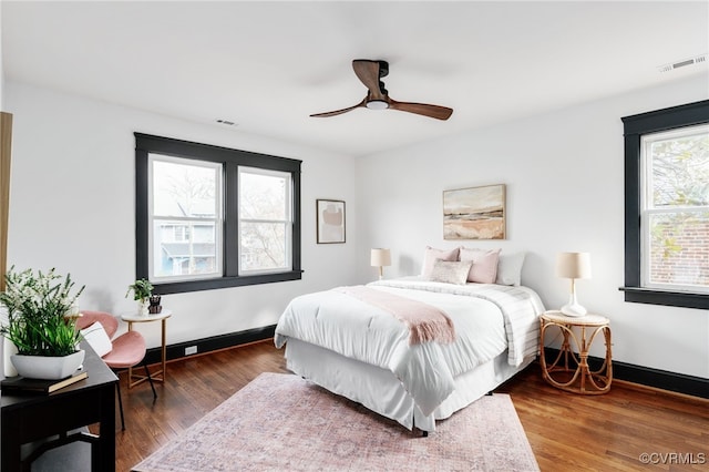 bedroom with a ceiling fan, baseboards, visible vents, and wood finished floors