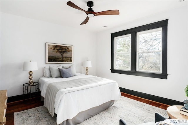 bedroom featuring visible vents, ceiling fan, baseboards, and wood finished floors