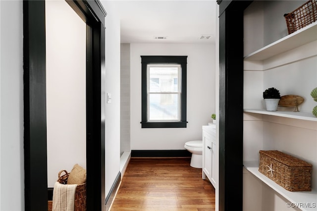 bathroom with toilet, wood finished floors, visible vents, and baseboards