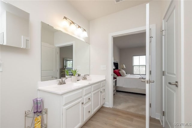 full bathroom featuring double vanity, wood finished floors, ensuite bath, and a sink