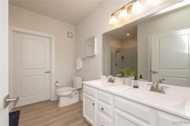 full bathroom with wood finished floors, a stall shower, a sink, and toilet