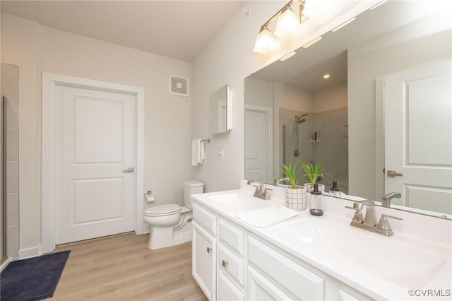 bathroom with a sink, a shower stall, toilet, and wood finished floors