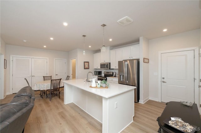 kitchen featuring light countertops, appliances with stainless steel finishes, light wood-style floors, and white cabinets