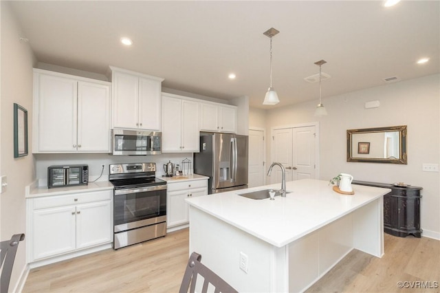 kitchen featuring white cabinetry, appliances with stainless steel finishes, light wood-style flooring, and a sink