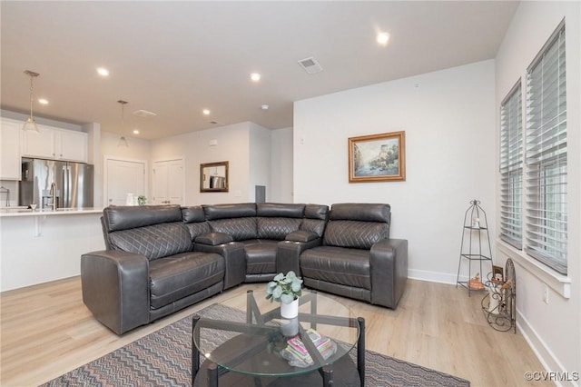 living room with light wood-style flooring, visible vents, baseboards, and recessed lighting