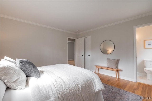 bedroom featuring ornamental molding, wood finished floors, and ensuite bathroom