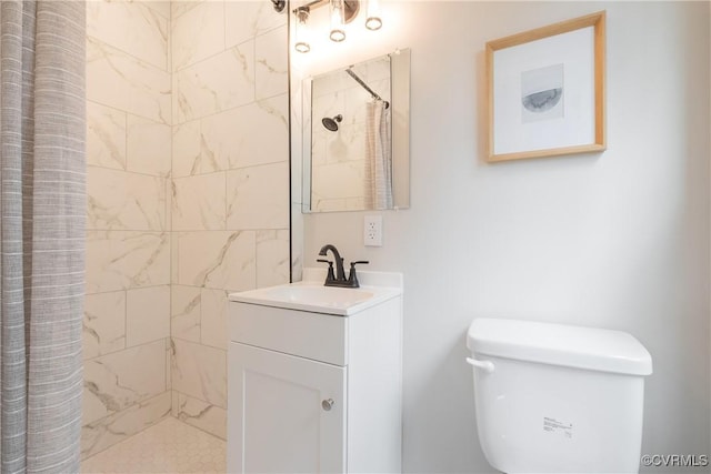 bathroom featuring toilet, a tile shower, and vanity