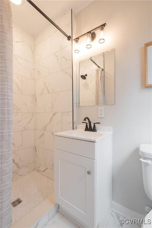 full bath with toilet, vanity, baseboards, marble finish floor, and a tile shower