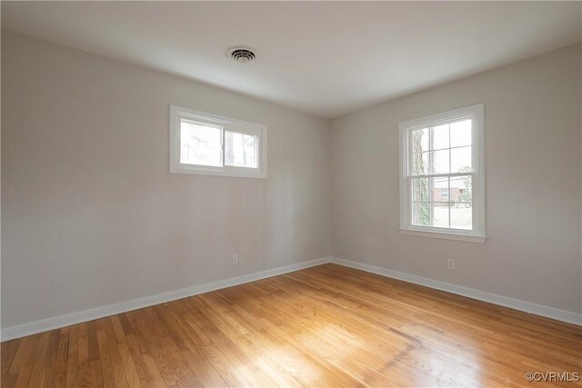 spare room featuring visible vents, plenty of natural light, light wood-style flooring, and baseboards