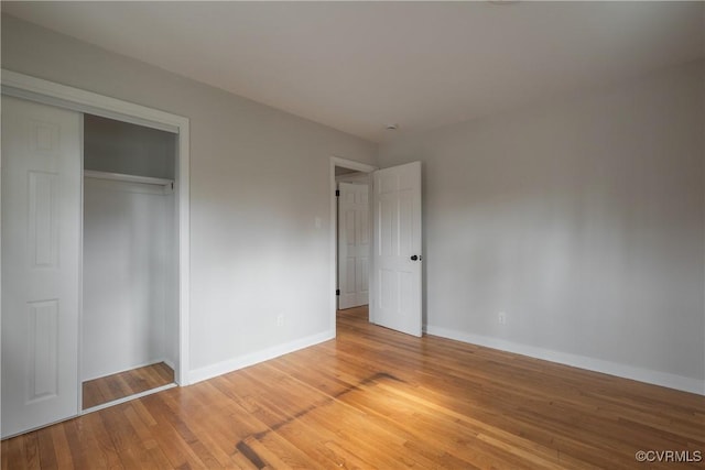 unfurnished bedroom featuring a closet, baseboards, and light wood finished floors