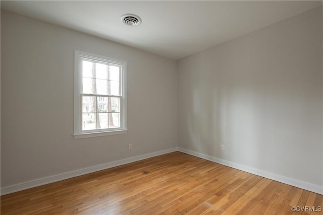 unfurnished room featuring visible vents, light wood-style flooring, and baseboards