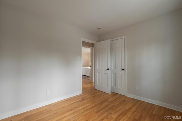 unfurnished bedroom featuring light wood-style floors, a closet, and baseboards