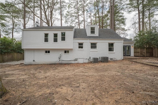 back of property with central AC unit, fence, and brick siding