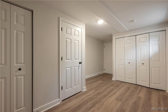 unfurnished bedroom featuring light wood finished floors, a closet, and baseboards