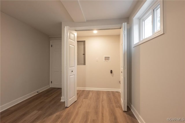 hall featuring baseboards, electric panel, and light wood finished floors