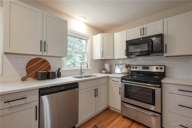 kitchen with stainless steel appliances, tasteful backsplash, a sink, and light countertops