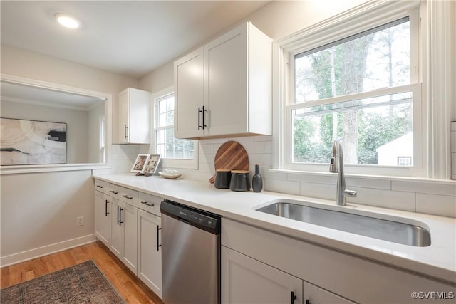 kitchen featuring a sink, white cabinetry, light wood-type flooring, backsplash, and dishwasher