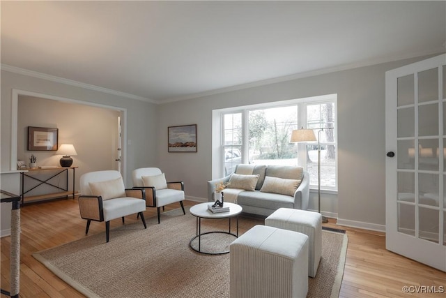 living room with baseboards, light wood-type flooring, and crown molding