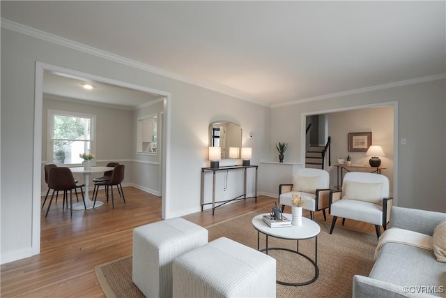 living area with light wood-type flooring, crown molding, and stairs