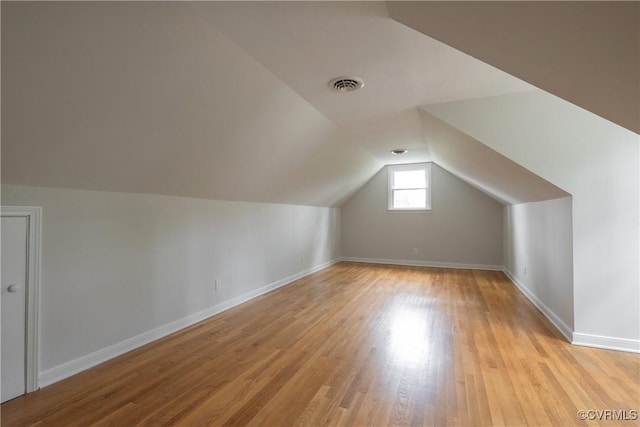 additional living space with lofted ceiling, light wood-style flooring, visible vents, and baseboards