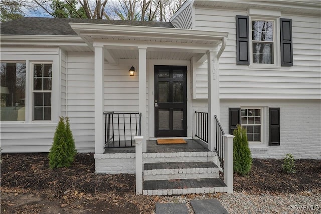 doorway to property featuring roof with shingles and brick siding