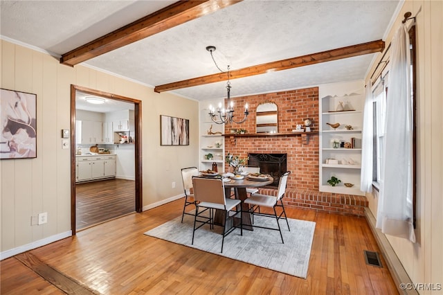 dining room with baseboards, built in features, hardwood / wood-style flooring, a textured ceiling, and beam ceiling