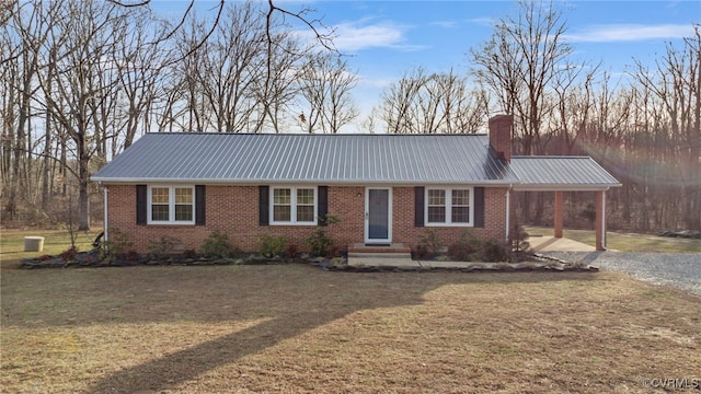 ranch-style home with metal roof, an attached carport, brick siding, a chimney, and gravel driveway