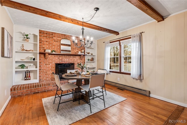 dining room featuring a textured ceiling, built in shelves, baseboard heating, beam ceiling, and wood-type flooring