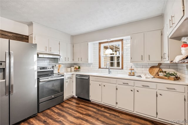 kitchen with tasteful backsplash, appliances with stainless steel finishes, dark wood-type flooring, under cabinet range hood, and a sink