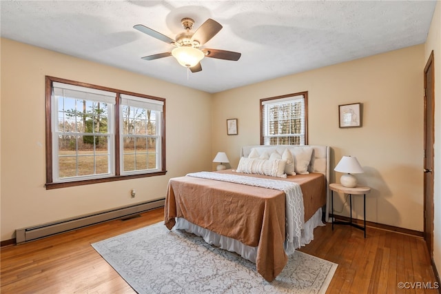 bedroom featuring hardwood / wood-style flooring, baseboards, a baseboard heating unit, and ceiling fan