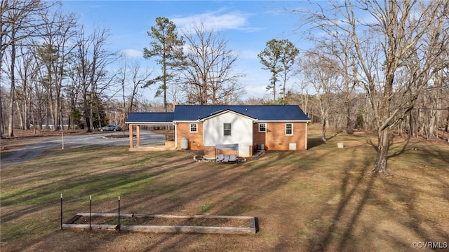 view of front of property with a front yard, brick siding, a vegetable garden, and a chimney