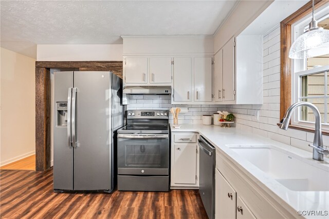 kitchen featuring under cabinet range hood, dark wood-type flooring, a sink, white cabinetry, and appliances with stainless steel finishes