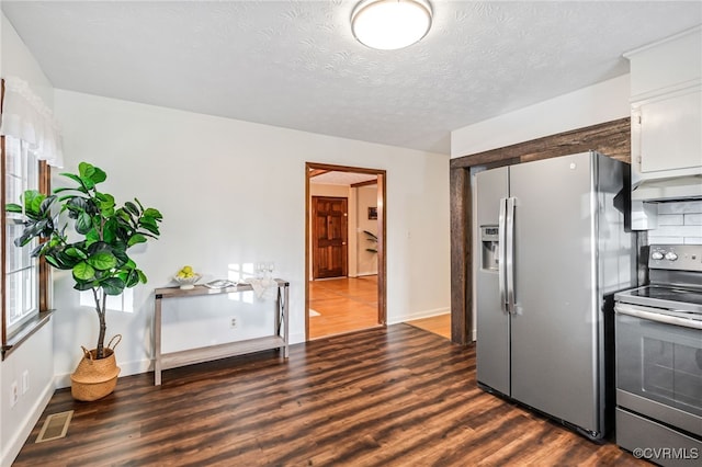 kitchen with a textured ceiling, under cabinet range hood, stainless steel appliances, visible vents, and dark wood finished floors