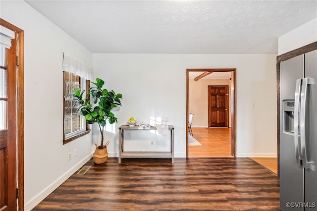 interior space with a textured ceiling, wood finished floors, visible vents, and baseboards