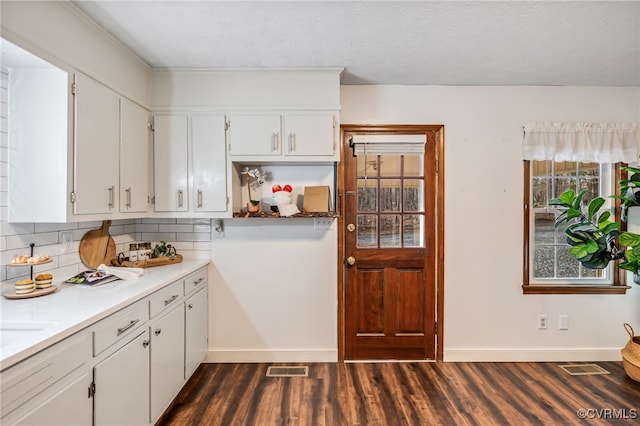 kitchen with dark wood-style floors, visible vents, light countertops, backsplash, and white cabinets