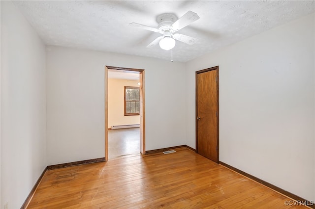 empty room with light wood-type flooring, visible vents, baseboards, and a baseboard radiator