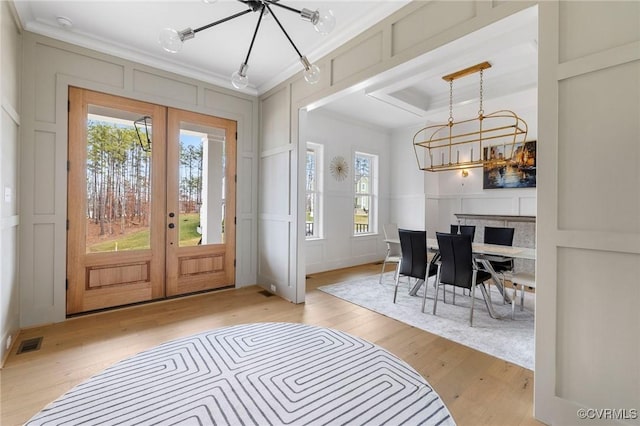 foyer entrance featuring crown molding, french doors, and a decorative wall