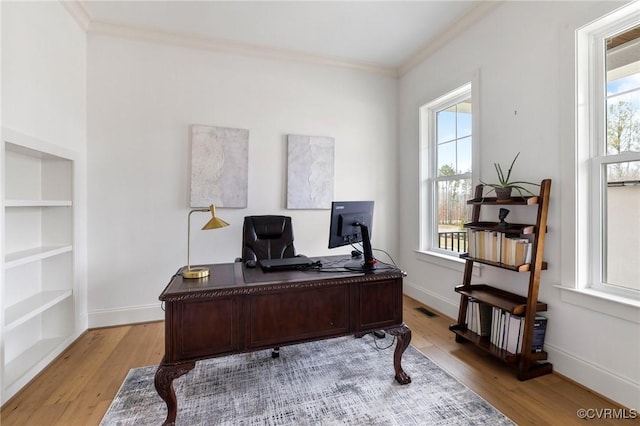 office area with light wood-style floors, a healthy amount of sunlight, crown molding, and visible vents