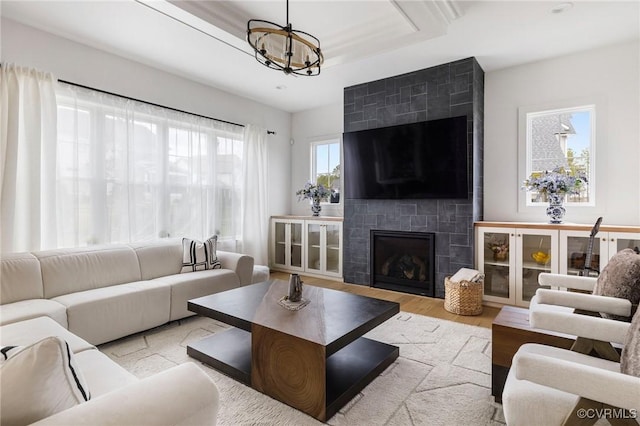 living area featuring a chandelier, wood finished floors, a fireplace, and a raised ceiling