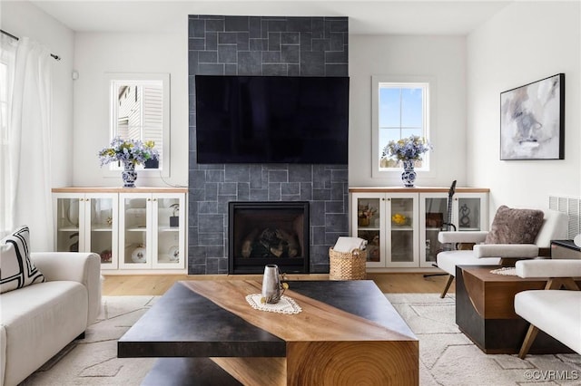 living room with a fireplace, wood finished floors, and visible vents