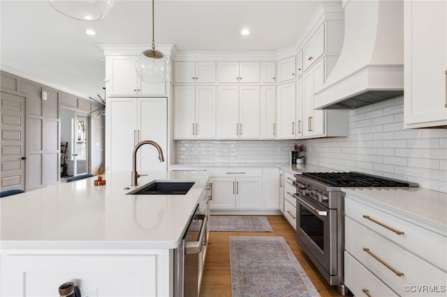 kitchen featuring light countertops, premium range hood, stainless steel range, and a sink