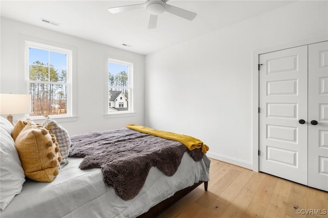 bedroom with a ceiling fan, baseboards, visible vents, and light wood finished floors