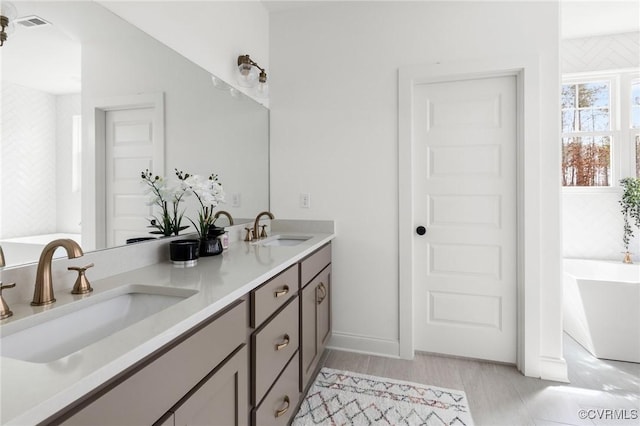 full bathroom with a freestanding tub, a sink, and double vanity