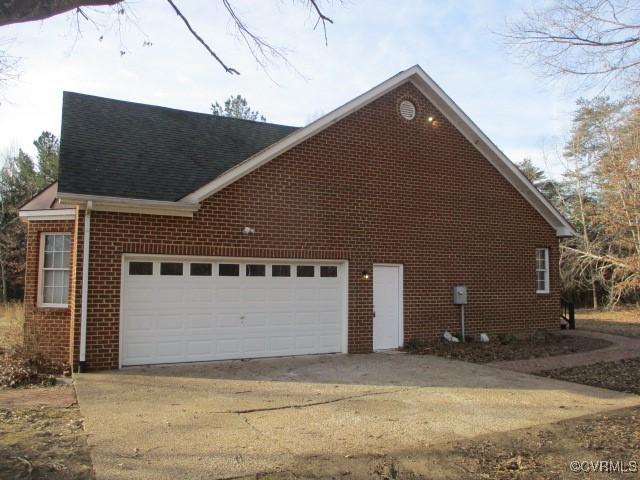 view of home's exterior with a garage, brick siding, driveway, and a shingled roof