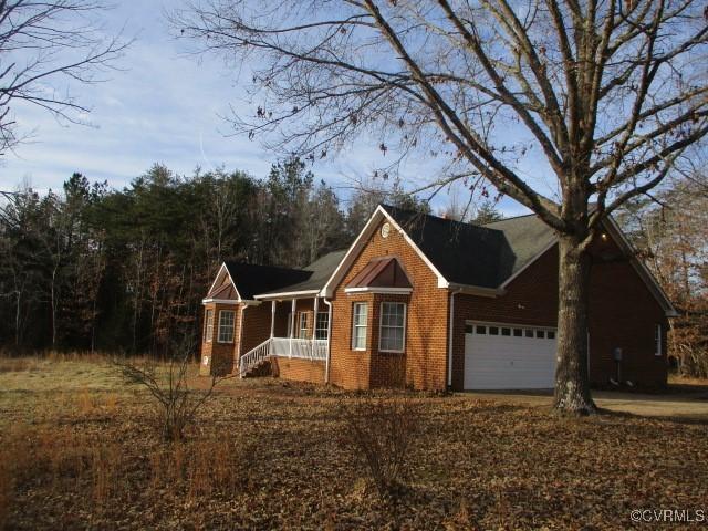 view of front of home with a garage, concrete driveway, brick siding, and covered porch