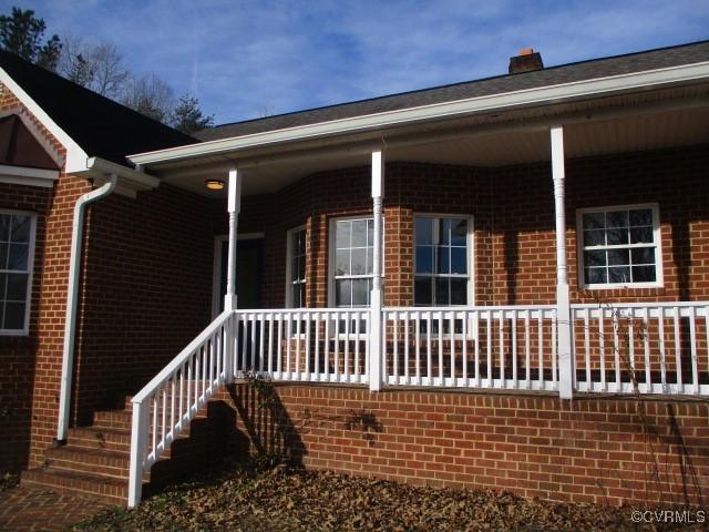 view of home's exterior with covered porch, brick siding, and stairway