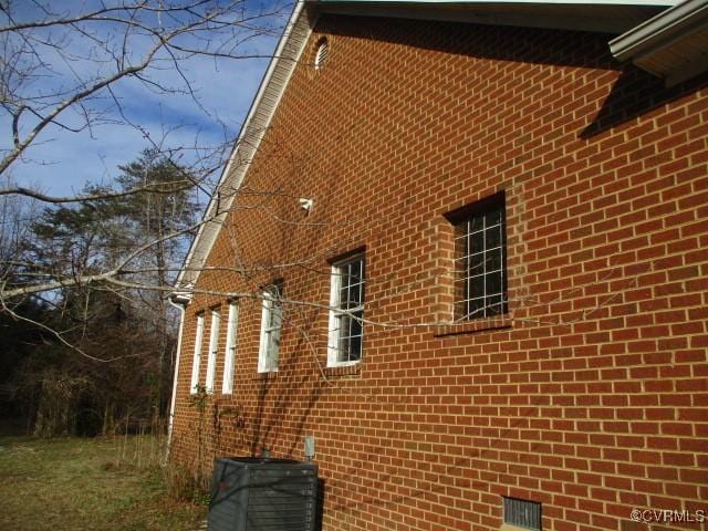 view of side of property featuring brick siding and central AC unit