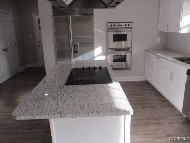 kitchen featuring appliances with stainless steel finishes, wood finished floors, light stone countertops, and white cabinets