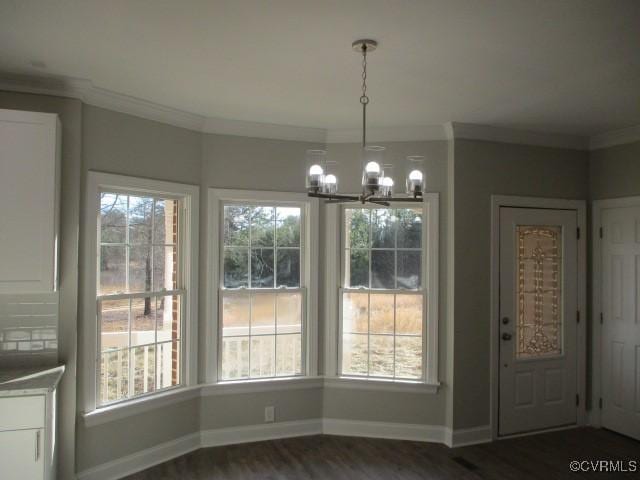 unfurnished dining area with a healthy amount of sunlight, ornamental molding, and dark wood-style flooring