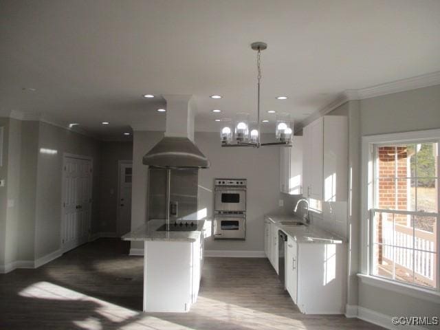 kitchen with stainless steel appliances, white cabinetry, a sink, and wall chimney exhaust hood